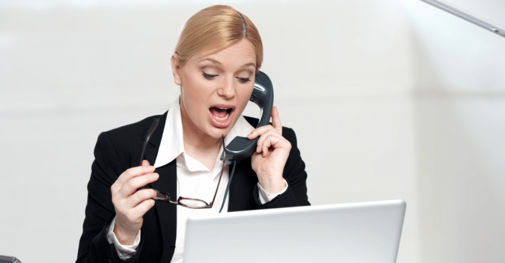 A women on the phone on her left hand and with her glasses off on her right hand. She has a white laptop in front of her. She is convincing someone through the phone.