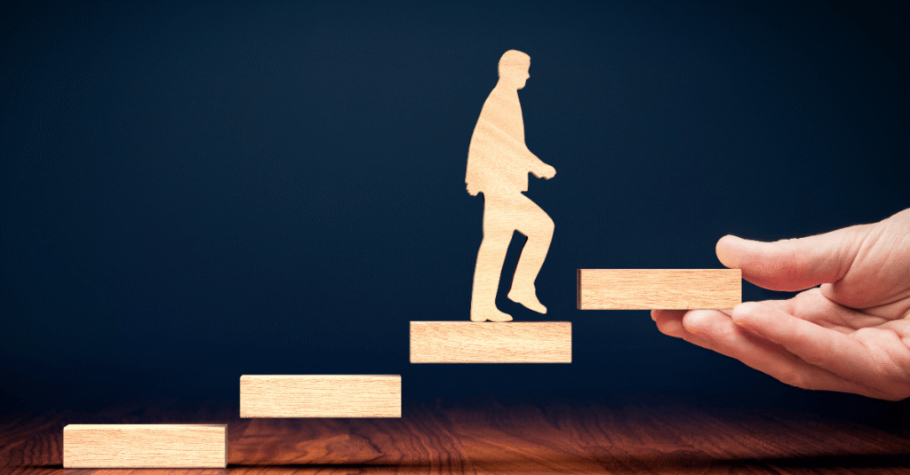 An animation where a man shaped out of wood is walking up a fictive stair to the top. A hand is holding the top of the stairs.